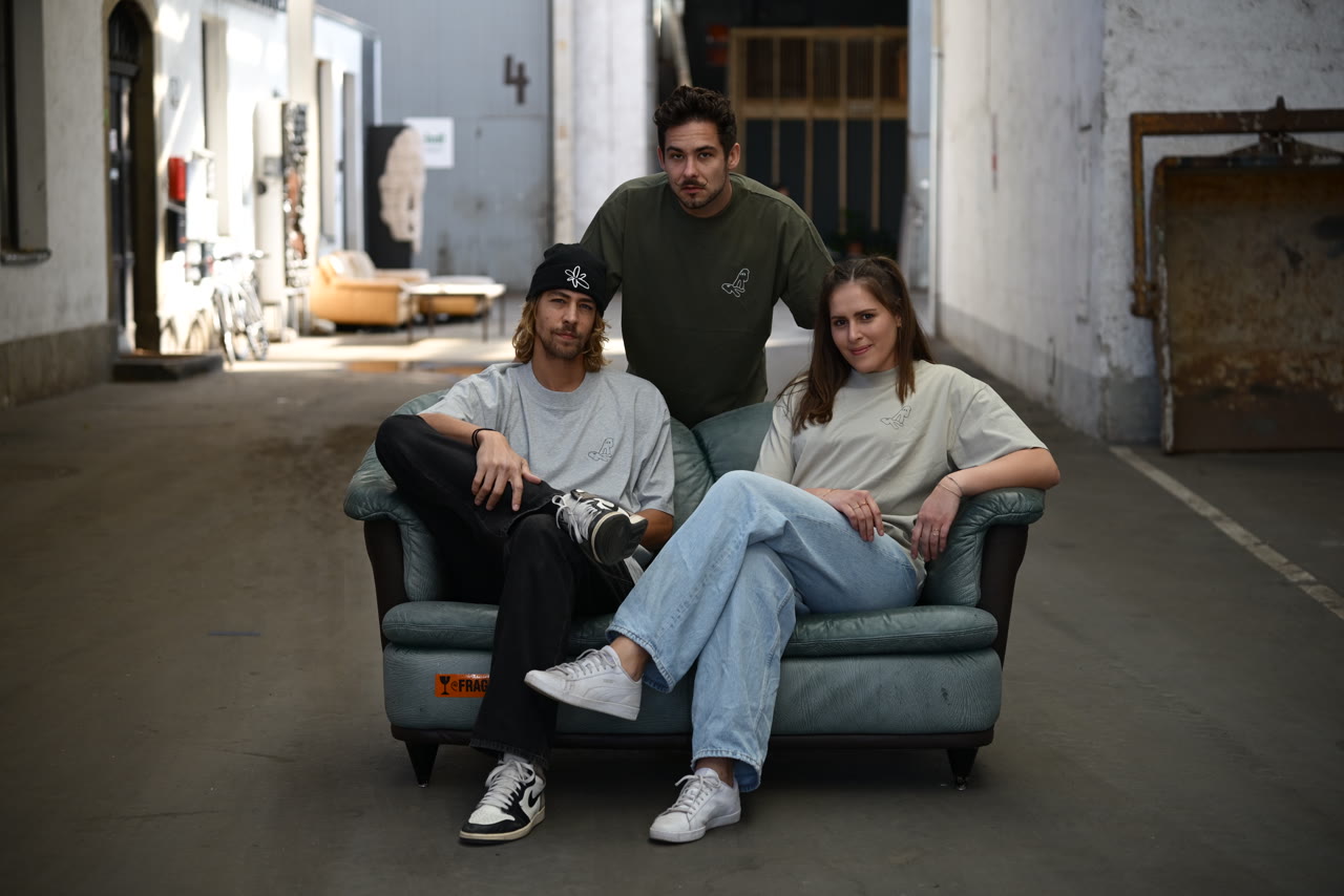 Drei Personen tragen die Alprec T-Shirts in Heather Grey, Olive und Sand.